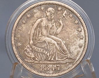May include: A silver coin from 1847, featuring a seated woman holding a staff and shield with the word "LIBERTY". The coin is encased in a clear holder, with stars around the edge.