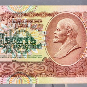 May include: A 1991 10-ruble banknote, displaying a portrait of a man and the number "10". The note is predominantly red, green, and brown, with detailed patterns and the Soviet Union emblem.
