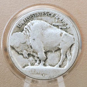 May include: A silver US Buffalo nickel coin with the year 1913 on the bottom. The coin is in a plastic coin holder.