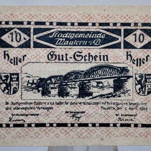 Peut inclure: Un ancien billet de banque avec une bordure noire et rouge, avec le texte "Gut-Schein" et "10 Heller". Le billet comprend une illustration détaillée d'un pont et du texte en allemand. Le billet est daté du 2 avril 1920.