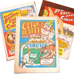 May include: Three vintage Clyde Beatty-Cole Bros. Circus magazines and programs featuring colorful illustrations of clowns, tigers, and circus performers. The covers display bold typography, circus imagery, and the text World's Largest Circus.
