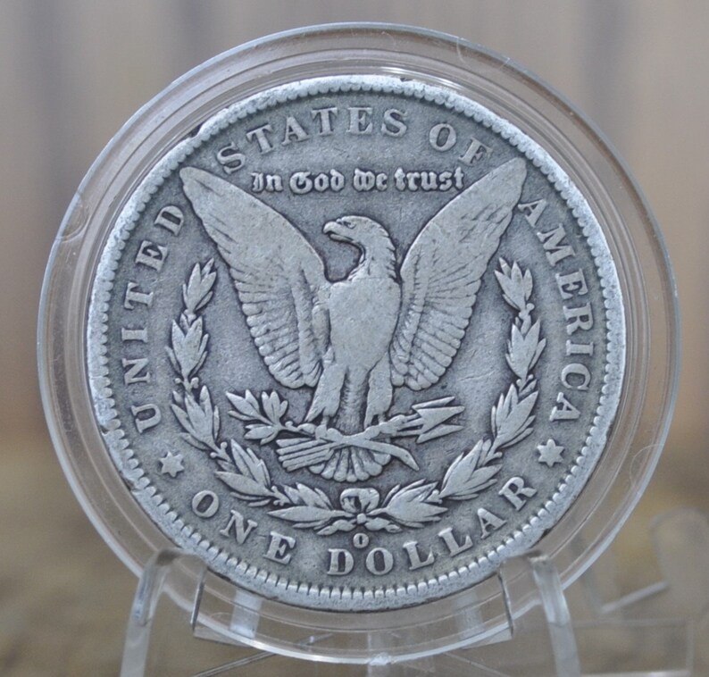 May include: A silver dollar coin with an eagle design. The coin has the words "United States of America" and "In God We Trust" inscribed on it. The coin also has the words "One Dollar" inscribed on it.