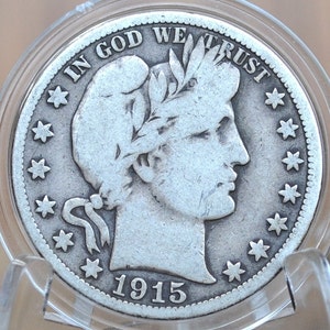 May include: A silver coin from 1915, featuring a profile of a person with a laurel wreath and the inscription "IN GOD WE TRUST." The coin is surrounded by stars and is encased in a clear protective holder.