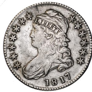 May include: A silver coin from 1817 featuring a profile of a woman with the word "LIBERTY" above her head. The coin is ringed with stars and has the date "1817" at the bottom. The coin has a worn, antique appearance.