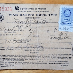 Puede incluir: Libro de Racionamiento de Guerra Dos vintage de la Oficina de Administración de Precios de los Estados Unidos. El documento es de color canela con texto negro y rojo, y un sello azul. Incluye información personal y advertencias.