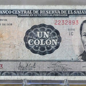 May include: A vintage one Colón banknote from El Salvador, featuring a portrait of a man on the right and the text "UN COLON" in the center. The note includes the text "EL BANCO CENTRAL DE RESERVA DE EL SALVADOR" and the date "24 DE OCTUBRE DE 1972".
