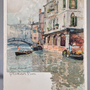 May include: Vintage postcard featuring a watercolor painting of Venice, Italy. The artwork depicts buildings along a canal, a bridge, and boats. The artist's signature, "Manuel Wielandt," and the text "VENEZIA S. SOFTA" are visible.