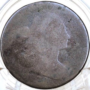 May include: A close-up of a copper coin with a profile of a person on the obverse side. The coin is in a plastic coin holder.