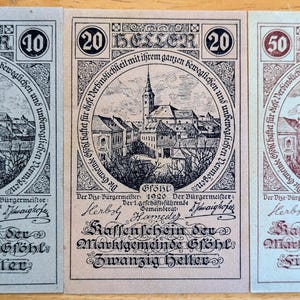 May include: Three antique banknotes, each with a different value: 10, 20, and 50 Heller. The notes display a detailed illustration of a town with a church and German text. The notes are in shades of blue, brown, and red.