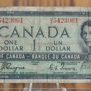 May include: A vintage Canadian one dollar bill featuring a portrait of Queen Elizabeth II. The bill is green and blue with the text "CANADA" and "ONE DOLLAR" printed in red. The bill is dated 1954 and has the serial number 5423061.