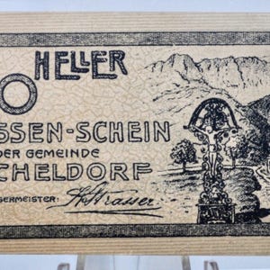 May include: A vintage 20 Heller note from Micheldorf, with a detailed black and white illustration of a mountain landscape, a crucifix, and a small building. The note has text in German.