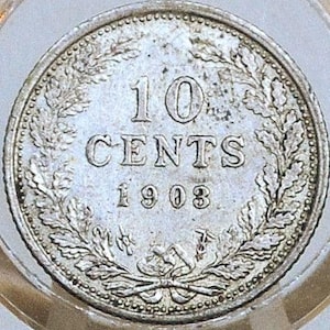 May include: A silver 1903 ten-cent coin, featuring the text "10 CENTS" and the year. The coin is surrounded by a wreath design and is encased in a clear holder. The coin's details are visible, showcasing its age and design.