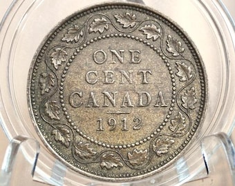 May include: A silver Canadian one cent coin from 1912. The coin features a wreath of maple leaves around the edge and the words "ONE CENT CANADA 1912" in the center.