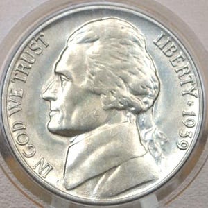 Könnte beinhalten: Eine silberne US-amerikanische Halbdolar-Münze mit dem Profil eines Mannes auf der Vorderseite. Die Münze trägt die Aufschrift "IN GOD WE TRUST" und "LIBERTY 1939".