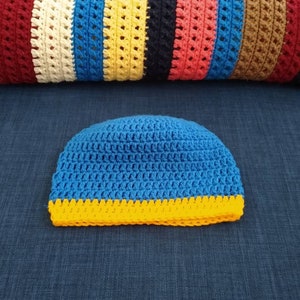 May include: A blue crocheted hat with a yellow crocheted brim.
