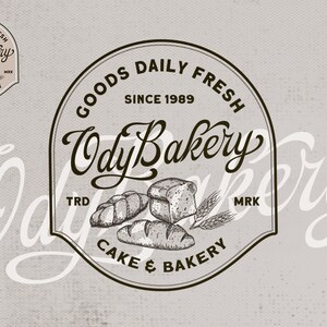 May include: Black and white logo for a bakery called "Ody Bakery." The logo features the bakery's name in a stylized script font, the words "Goods Daily Fresh" and "Cake & Bakery" in a sans-serif font, and a drawing of bread and wheat.