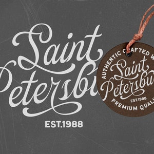 May include: A brown leather tag with white text that reads "Authentic Crafted Wear Saint Petersburg Est. 1988 Premium Quality". The tag is attached to a brown string.