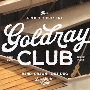 Puede incluir: Diseño gráfico con las palabras "Goldray CLUB" en una fuente blanca y estilizada. El texto se establece sobre un fondo oscuro con las palabras "New PROUDLY PRESENT" arriba y "HAND-DRAWN FONT DUO" y "Letterhend Studio" abajo.