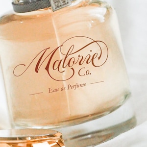 Peut inclure: Un flacon de parfum en verre transparent avec une &eacute;tiquette brune sur laquelle est inscrit "Matorie Co. Eau de Parfum".