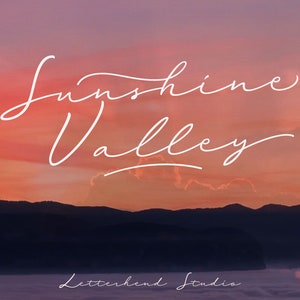 Puede incluir: Una puesta de sol sobre una cordillera con el texto "Sunshine Valley" escrito en una fuente blanca cursiva. El texto "Letterhend Studio" está escrito en una fuente más pequeña debajo de la cordillera.