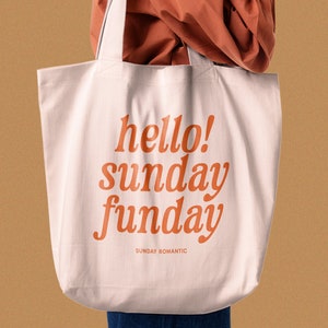 May include: A white tote bag with orange text that reads "hello! sunday funday" and "SUNDAY ROMANTIC" in a smaller font.
