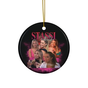 Könnte beinhalten: Ein runder Keramik-Anhänger mit einem Collage von Bildern von Stassi Schroeder aus der Reality-TV-Show Vanderpump Rules. Der Anhänger ist schwarz mit einem rosa und weißen Design. Der Text "Stassi Schroeder" ist in rosa Buchstaben oben auf dem Anhänger geschrieben.