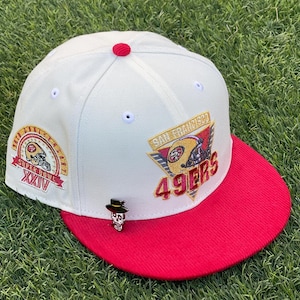 Peut inclure: Casquette de baseball blanche et rouge avec le logo des 49ers de San Francisco et l'écusson du Super Bowl XXIV. La casquette a un bord rouge et une petite épingle de crâne avec un chapeau.