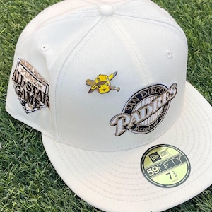 May include: Cream-colored baseball cap with embroidered San Diego Padres logo and a 1992 All-Star Game patch. Features a Pikachu pin wearing a baseball cap and holding a bat. The hat size is 7 3/8.