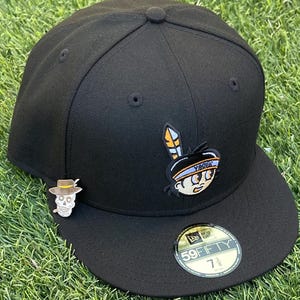 May include: Black fitted baseball cap with a cartoon graphic of a Native American figure and the word "YAQUIS". A skull pin with a hat is on the side. The cap has a 59FIFTY sticker.