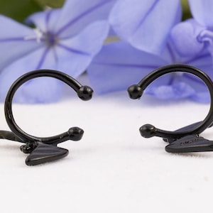 Pu&ograve; includere: Un paio di orecchini a cerchio neri con un design triangolare. Gli orecchini sono aperti e pronti per essere indossati.