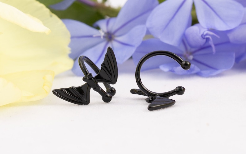 Pu&ograve; includere: Due orecchini neri, uno a forma di pipistrello e l'altro a forma di curva semplice con un piccolo triangolo all'estremit&agrave;.