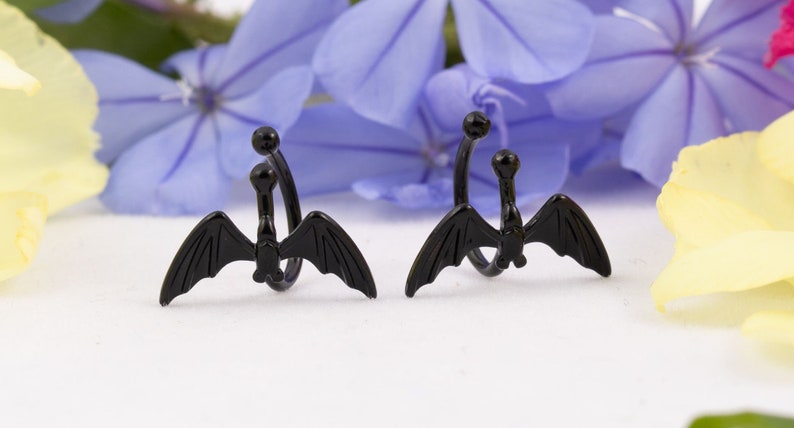 Pu&ograve; includere: Un paio di orecchini a cerchio per orecchie a forma di pipistrello nero. Gli orecchini sono in metallo e hanno un design a spirale. Le ali di pipistrello sono dettagliate e hanno una finitura nera.