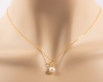 May include: A delicate gold chain necklace with a single white pearl pendant.