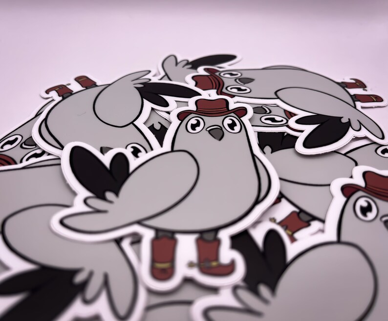 Op de afbeelding: Een stapel grijze en witte vogel stickers met rode cowboyhoeden en laarzen. De stickers zijn cartoonachtige illustraties van vogels die cowboyhoeden en laarzen dragen.