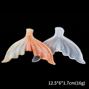 Puede incluir: Dos moldes de cola de sirena. Uno es un degradado de melocot&oacute;n y dorado, el otro es azul p&aacute;lido. Las colas tienen un dise&ntilde;o detallado y texturizado con peque&ntilde;os detalles en forma de cuentas. Dimensiones: 12,5 x 6 x 1,7 cm (16g).