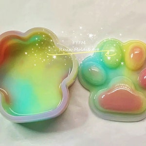 Pu&ograve; includere: Uno stampo in resina a forma di impronta di zampa di colore arcobaleno con un coperchio abbinato. Lo stampo &egrave; aperto e il coperchio &egrave; posto accanto ad esso. Lo stampo &egrave; realizzato in resina trasparente e presenta un design a spirale arcobaleno. Il coperchio &egrave; anch'esso realizzato in resina trasparente e presenta un design a spirale arcobaleno. Lo stampo &egrave; perfetto per realizzare oggetti in resina.