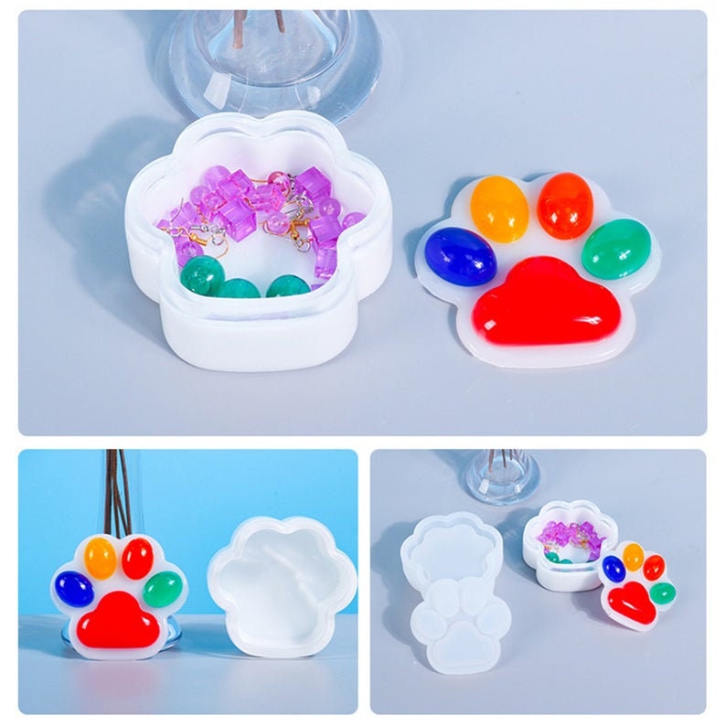 Pu&ograve; includere: Un set di due stampi in silicone a forma di zampa per realizzare gioielli in resina o altri oggetti artigianali. Gli stampi sono bianchi e presentano un design dettagliato di impronta di zampa. Uno stampo &egrave; mostrato con un'impronta di zampa in resina finita con accenti colorati.