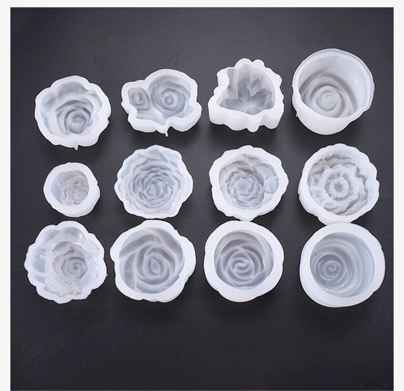 May include: A selection of white silicone rose-shaped moulds. The moulds vary in size and design, with detailed petal patterns. Ideal for crafting, these moulds offer a versatile option for creating decorative elements.