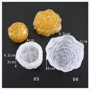 May include: The image shows three rose-shaped molds and two finished resin castings. The molds are white, and the castings are gold. The molds are labelled 05 and 06, with measurements of 3 cm, 4 cm, 4.5 cm, 6.3 cm, and 7 cm.