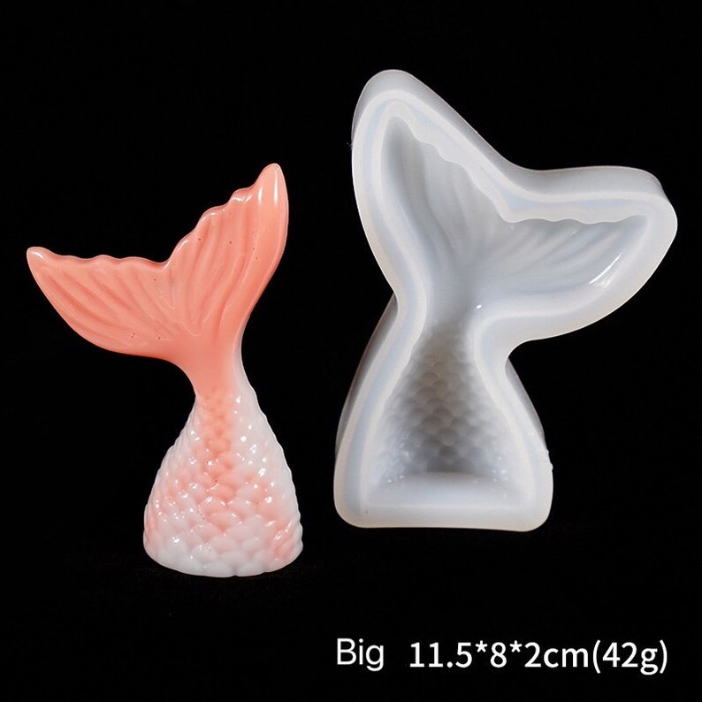 Puede incluir: Una figura de cola de sirena rosa y blanca junto a un molde de silicona de cola de sirena. La figura es de color rosa claro con una base blanca. El molde de silicona es blanco transl&uacute;cido. El texto "Big 11.5*8*2cm(42g)" est&aacute; en la parte inferior.