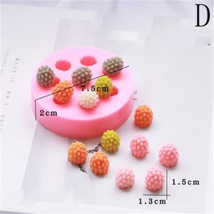 Op de afbeelding: Roze siliconen mal met 7 ronde holtes voor het maken van kleine, ronde snoepjes. De mal is 7,5 cm in diameter en 2 cm hoog. Er zijn 10 kleine, ronde snoepjes in verschillende kleuren, waaronder roze, oranje, geel en bruin. Elk snoepje is 1,5 cm in diameter en 1,3 cm hoog.
