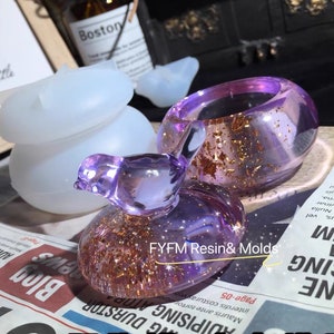 May include: A set of three resin molds for crafting jewelry. The molds are in the shape of a bird, a ring, and a small round object. The molds are clear and show the details of the finished product. The molds are made by FYFM Resin & Molds.