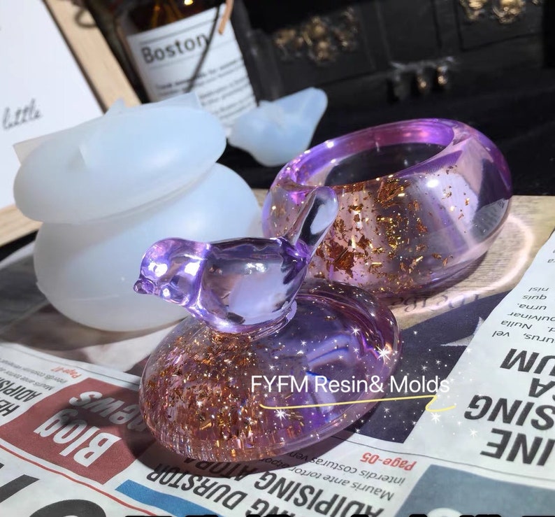 May include: A set of three resin molds for crafting jewelry. The molds are in the shape of a bird, a ring, and a small round object. The molds are clear and show the details of the finished product. The molds are made by FYFM Resin & Molds.