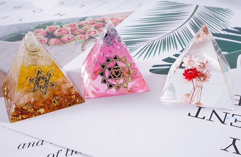 Pu&ograve; includere: Tre ornamenti a forma di piramide in vetro trasparente con diversi design. La prima piramide &egrave; riempita di glitter dorati e un design geometrico. La seconda piramide &egrave; rosa con un design a forma di cuore e stella dorati. La terza piramide &egrave; trasparente con fiori secchi all'interno.