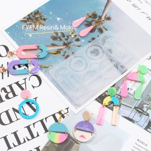 May include: A silicone mold for making resin earrings. The mold has six different shapes, including circles, ovals, and abstract shapes. There are also several pairs of finished resin earrings in various colors, including pink, blue, and green.