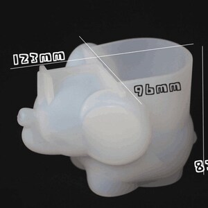 Puede incluir: Maceta de silicona blanca con forma de elefante con una maceta de 24,4 cm de alto. La maceta tiene 21,1 cm de ancho y 31,2 cm de largo.