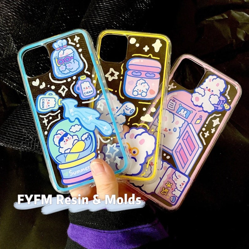 May include: Three clear phone cases with colorful cartoon designs. The cases feature a cloud with a face, a snow globe with a character inside, and a refrigerator with a character inside. The text "Summer" is on the snow globe case. The text "FYFM Resin & Molds" is at the bottom of the image.