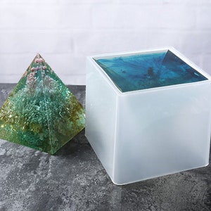 Pu&ograve; includere: Due stampi in resina trasparente, uno a forma di piramide e l'altro a forma di cubo. Lo stampo a forma di piramide &egrave; riempito con resina verde e blu, mentre lo stampo a forma di cubo &egrave; vuoto.