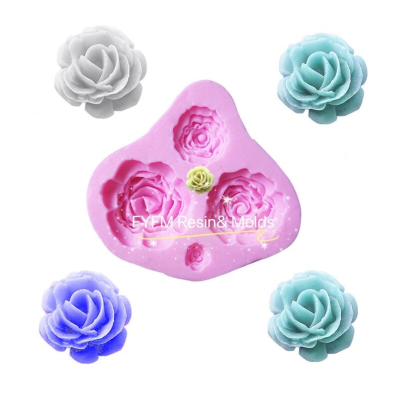 May include: A pink silicone mould with rose-shaped cavities and several finished rose-shaped objects in various colours. The mould has the text "EYEM Resin & Molds". The roses are in shades of white, blue, and teal.