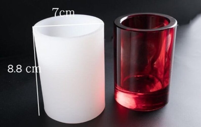 May include: Two cylindrical candle holders. One is frosted white, 8.8 cm tall and 7 cm wide. The other is a transparent, deep red. Both are made of glass and are suitable for home decor.